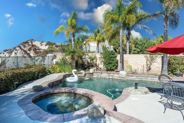 view of pool with a mountain view and an in ground hot tub