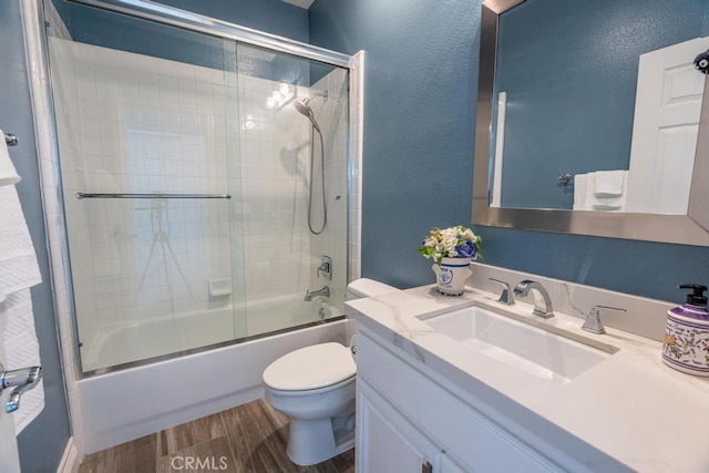 full bathroom with combined bath / shower with glass door, wood-type flooring, vanity, and toilet