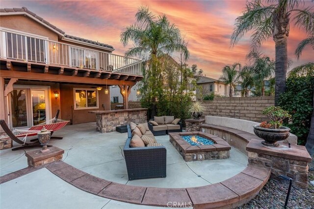 view of patio / terrace with a wooden deck, fence, and an outdoor living space with a fire pit