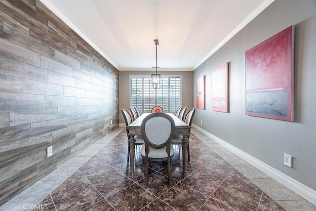 dining area with a chandelier, an accent wall, crown molding, and baseboards