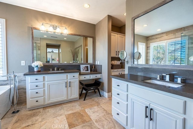 full bathroom featuring a soaking tub, two vanities, a sink, and recessed lighting