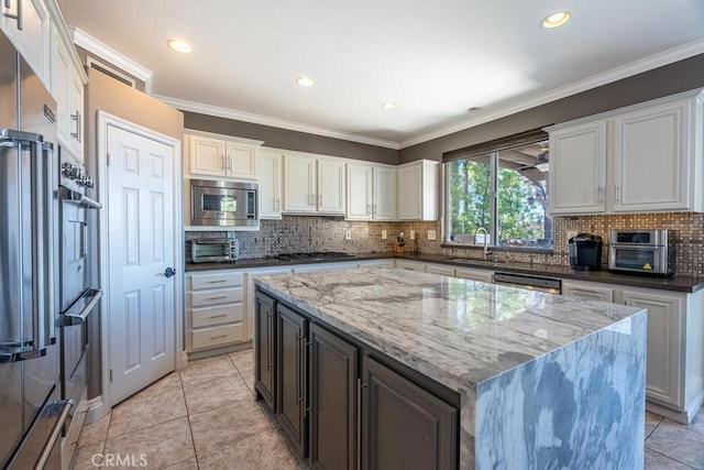 kitchen featuring crown molding, dark stone countertops, stainless steel appliances, and a sink