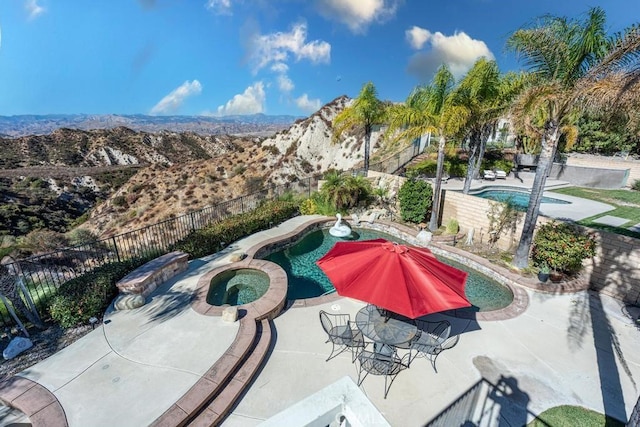 view of swimming pool featuring a fenced in pool, a patio area, a mountain view, an in ground hot tub, and a fenced backyard