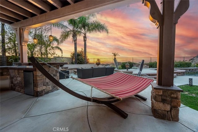 patio terrace at dusk featuring a fenced backyard, an outdoor living space, area for grilling, and an in ground hot tub