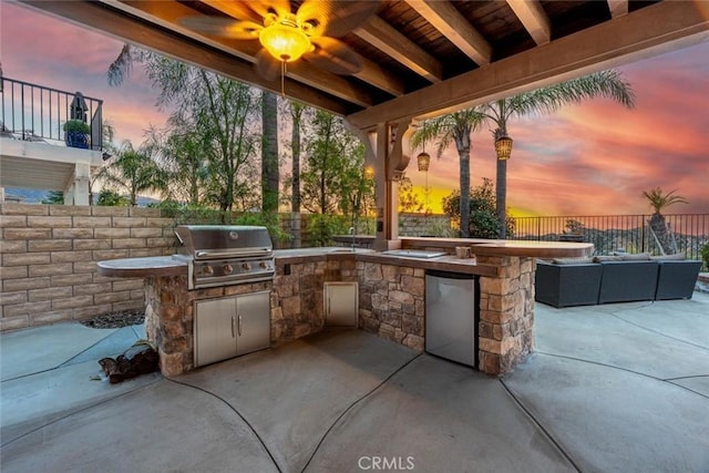 patio terrace at dusk with area for grilling, fence, and an outdoor living space