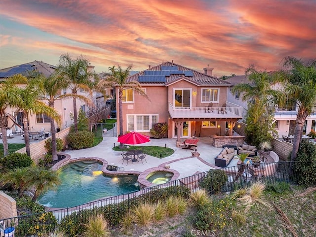 back of property with solar panels, a patio, a fenced backyard, an outdoor hangout area, and stucco siding