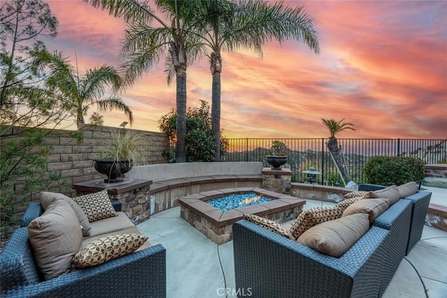 patio terrace at dusk featuring an outdoor fire pit and a fenced backyard