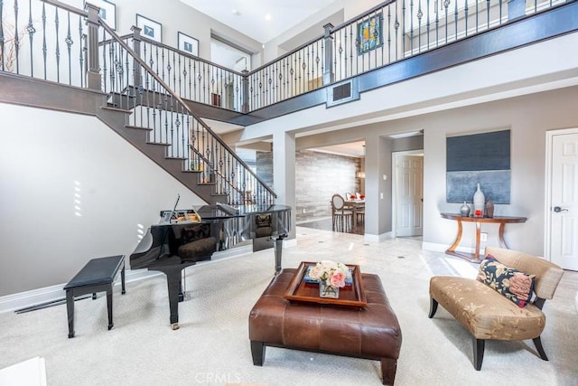 carpeted living room with a towering ceiling, baseboards, and stairs