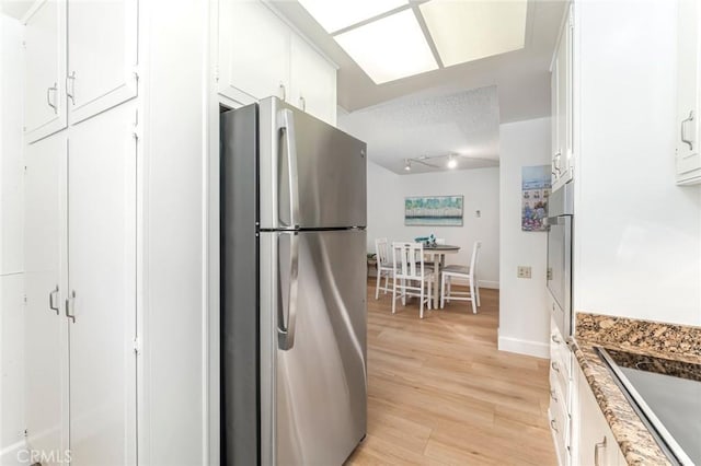 kitchen featuring light stone counters, white cabinets, light hardwood / wood-style floors, and appliances with stainless steel finishes