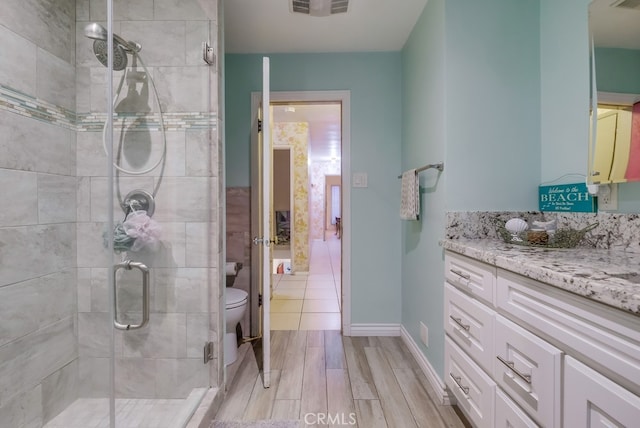 bathroom featuring toilet, a shower with door, and vanity