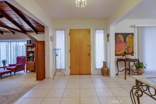 foyer featuring light colored carpet, lofted ceiling with beams, and wood ceiling