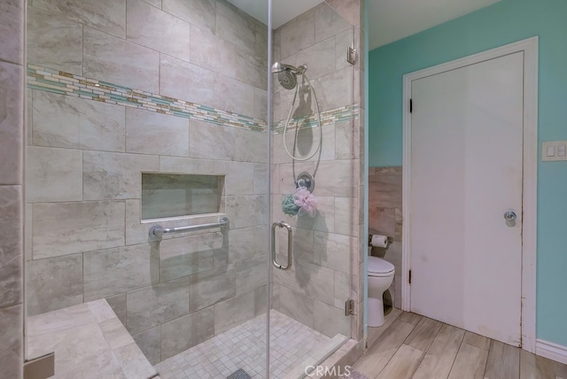 bathroom featuring a shower with shower door and toilet