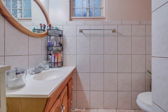 bathroom featuring toilet, tile walls, and vanity