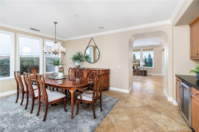 dining room featuring wine cooler, ornamental molding, and an inviting chandelier