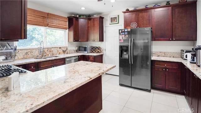 kitchen with sink, stainless steel appliances, tasteful backsplash, light stone counters, and light tile patterned floors