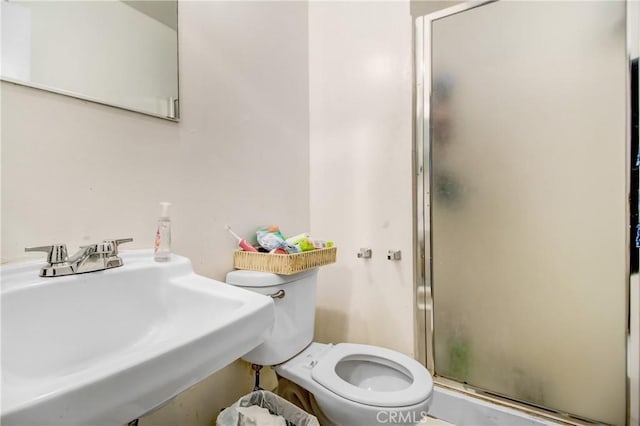 bathroom with sink, a shower with shower door, and toilet