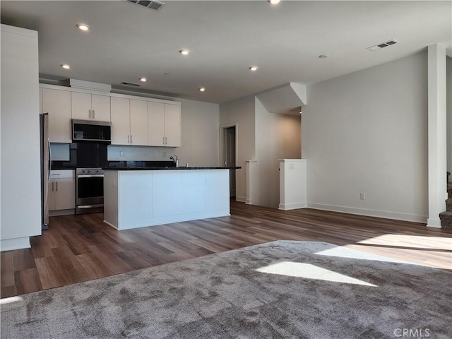 kitchen featuring white cabinets, a kitchen island with sink, appliances with stainless steel finishes, and dark wood-type flooring