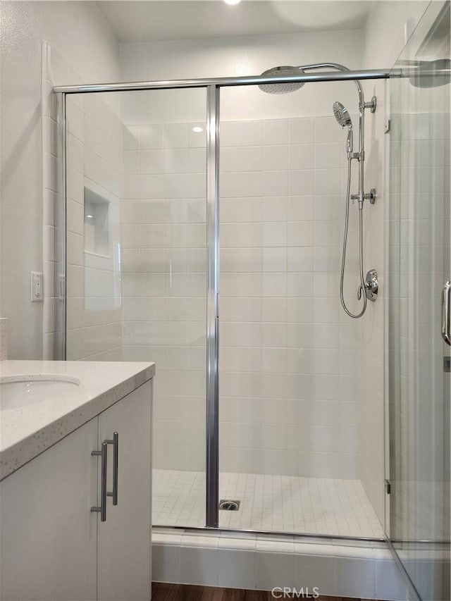 bathroom featuring hardwood / wood-style floors, vanity, and walk in shower