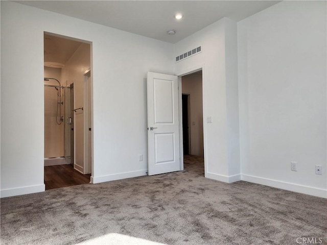 unfurnished bedroom featuring connected bathroom and dark carpet