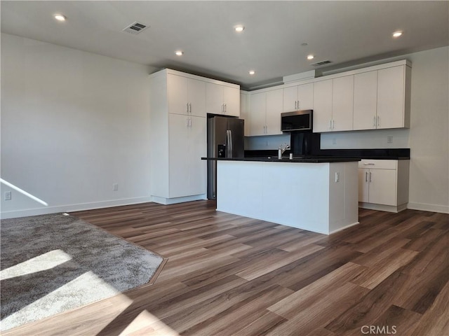 kitchen with a center island with sink, dark hardwood / wood-style floors, white cabinetry, and appliances with stainless steel finishes