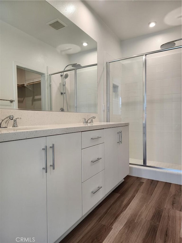 bathroom with hardwood / wood-style floors, vanity, and an enclosed shower