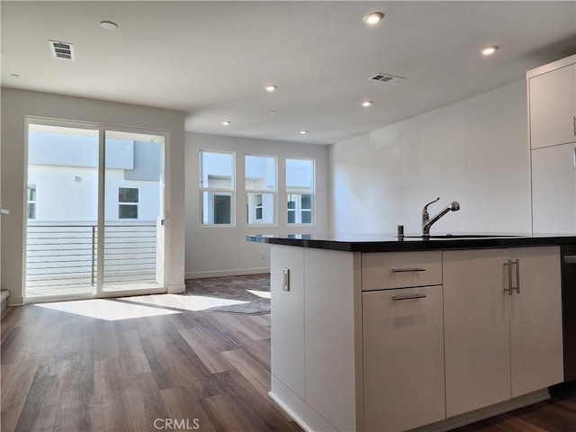 kitchen with sink, white cabinets, and wood-type flooring