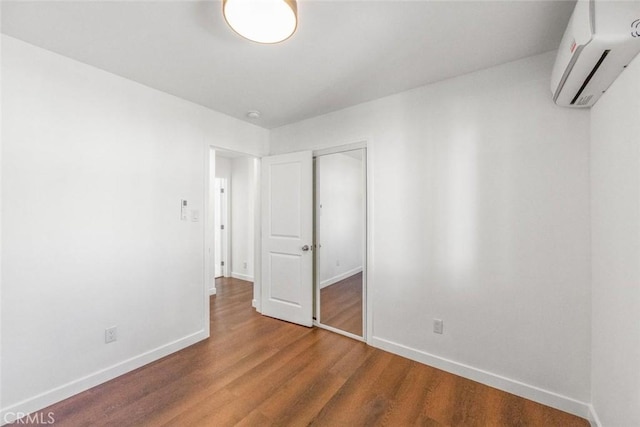 unfurnished bedroom featuring wood-type flooring and a wall mounted air conditioner