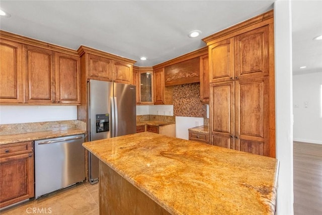 kitchen featuring backsplash, light stone counters, stainless steel appliances, and light hardwood / wood-style flooring