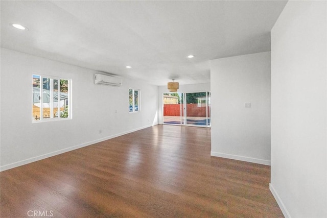 empty room with dark hardwood / wood-style flooring and an AC wall unit