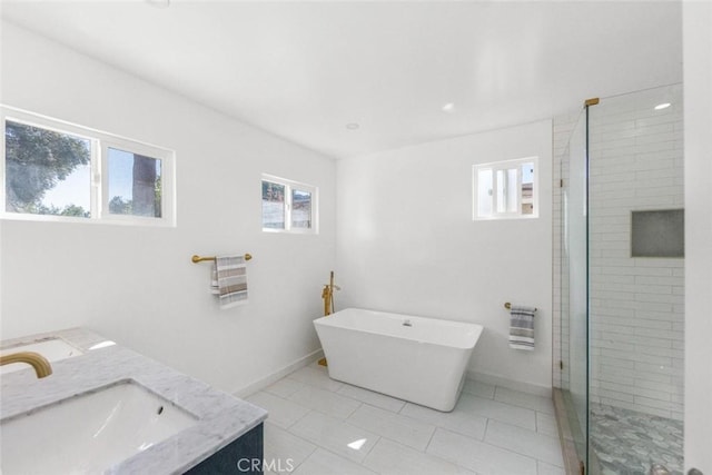 bathroom featuring plus walk in shower, vanity, tile patterned floors, and a wealth of natural light