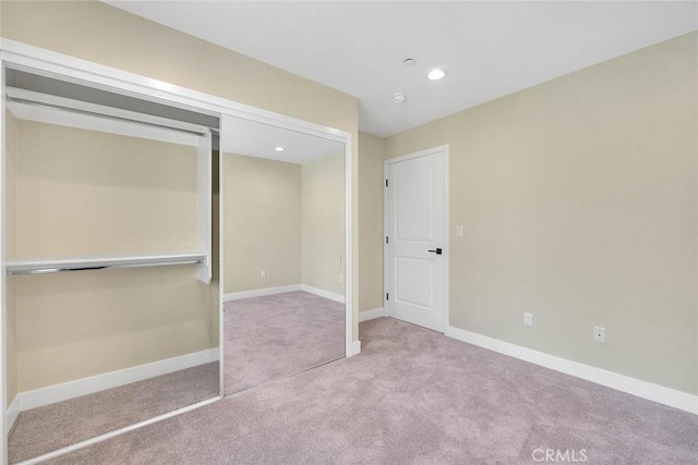 unfurnished bedroom with light colored carpet and a closet