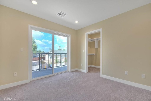 unfurnished bedroom featuring light colored carpet, access to exterior, a walk in closet, and a closet