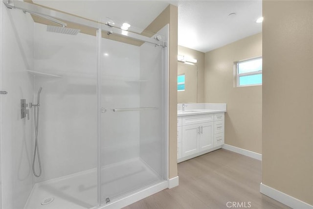 bathroom with wood-type flooring, vanity, and walk in shower