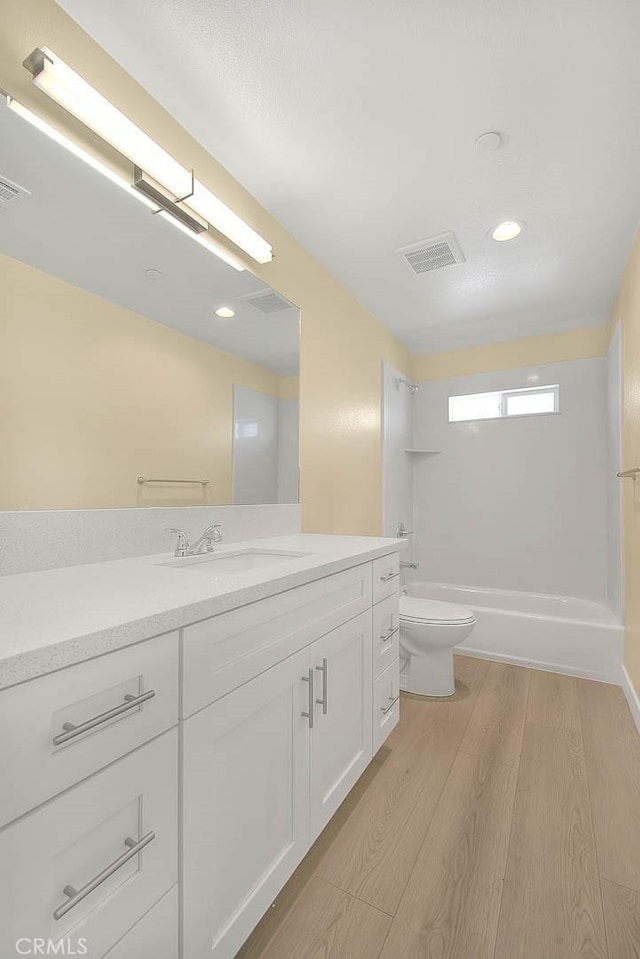 full bathroom with vanity, hardwood / wood-style floors, shower / bathtub combination, and toilet