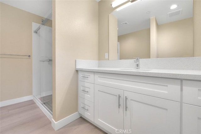 bathroom featuring hardwood / wood-style floors, vanity, and a shower with shower door