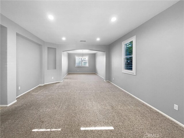 carpeted empty room with a notable chandelier