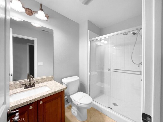 bathroom featuring tile patterned flooring, vanity, toilet, and an enclosed shower