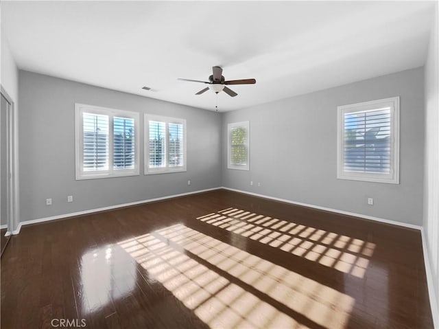 empty room with ceiling fan and dark wood-type flooring