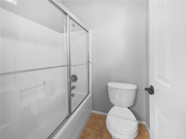 bathroom featuring tile patterned flooring, toilet, and enclosed tub / shower combo