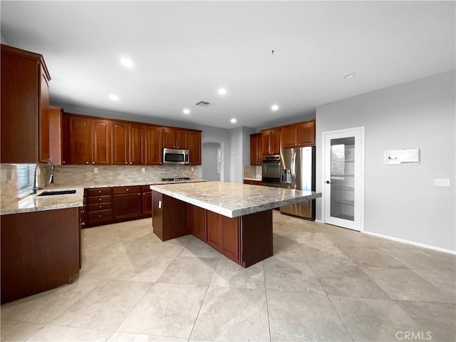 kitchen featuring appliances with stainless steel finishes, backsplash, sink, a kitchen island, and a breakfast bar area