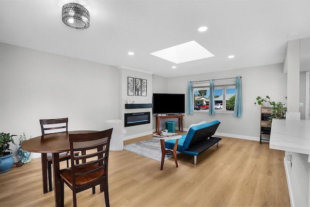 living room with light wood-type flooring, a skylight, and a notable chandelier