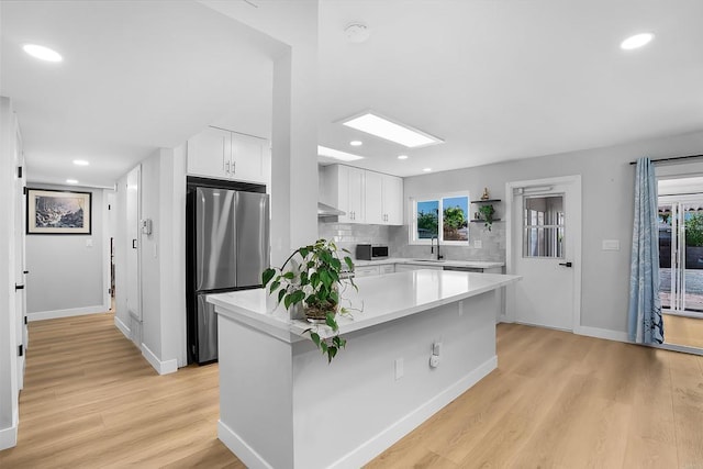 kitchen featuring white cabinets, a healthy amount of sunlight, light hardwood / wood-style floors, and stainless steel appliances