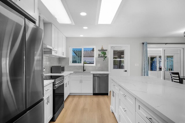 kitchen featuring white cabinetry, sink, stainless steel appliances, tasteful backsplash, and light hardwood / wood-style floors