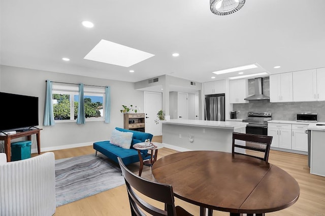 dining room featuring light hardwood / wood-style flooring and a skylight