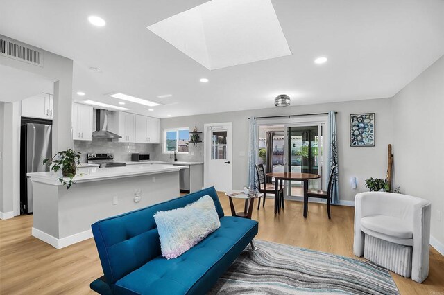 living room with a skylight and light hardwood / wood-style floors