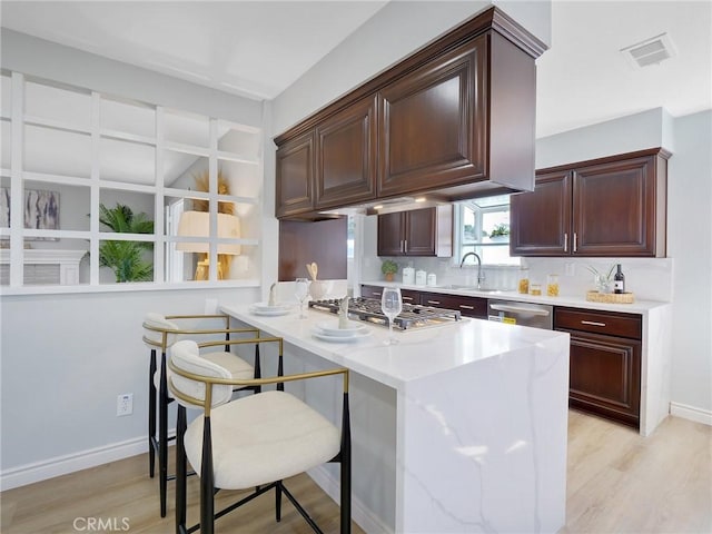 kitchen featuring a kitchen bar, appliances with stainless steel finishes, light hardwood / wood-style floors, and sink