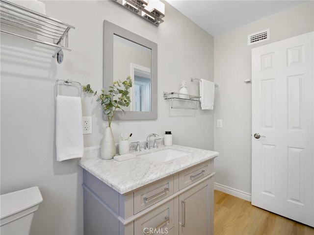 bathroom featuring vanity, wood-type flooring, and toilet