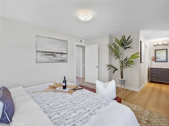 bedroom with light wood-type flooring and connected bathroom