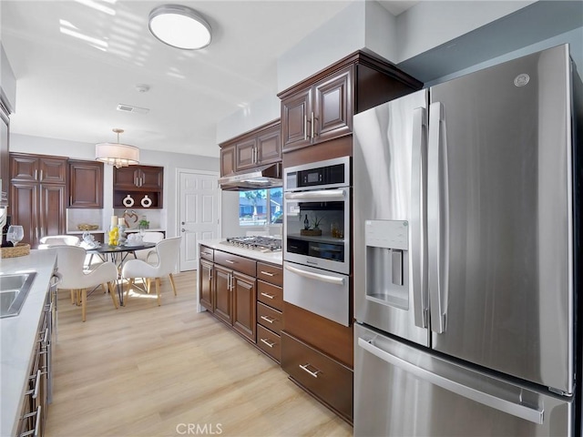 kitchen with decorative light fixtures, light hardwood / wood-style floors, sink, and appliances with stainless steel finishes