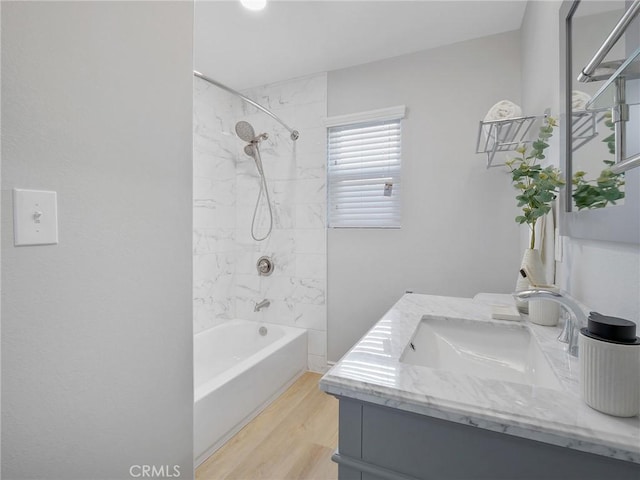 bathroom with hardwood / wood-style floors, vanity, and tiled shower / bath